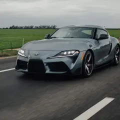 Szare auto sportowe jedzie po drodze. Ciemne felgi świetnie komponują się z nadwoziem, odpowiadając na pytanie: jaki kolor felg do srebrnego auta?