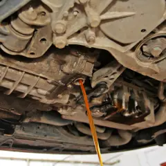 Płynny strumień oleju wypływa z automatycznej skrzyni biegów podczas jej wymiany.