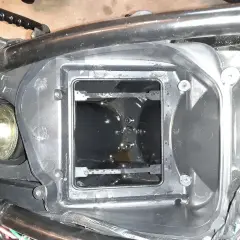 W komorze filtra powietrza motocykla widać ciemny olej w odmie.