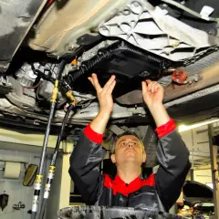 Mechanik wykonuje statyczną wymianę oleju w automatycznej skrzyni biegów, podłączając węże do układu.