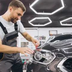 Fachowiec precyzyjnie wykonuje oklejanie folią lampy samochodu, dbając o każdy detal.