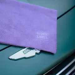 Fioletowy ręcznik z mikrofibry z logo Work Stuff leży na zielonym samochodzie Aston Martin. Dowiedz się, jak prać ręcznik z mikrofibry, by służył latami.