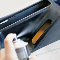 Ręka trzyma puszkę z farbą w sprayu, wykonując malowanie plastików. Odświeżanie wnętrza samochodu.
