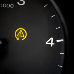 Żółty symbol ostrzegawczy na desce rozdzielczej: wykrzyknik w trójkącie i strzałka. To kontrola trakcji co to, gdy się świeci, warto sprawdzić auto.
