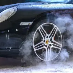Czarny Porsche z dymem unoszącym się z koła. Zastanawiasz się, ozonowanie samochodu ile czasu zajmuje?