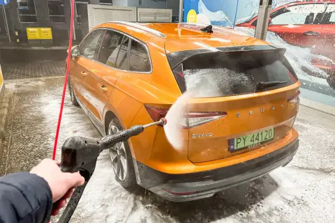 Jak dobrze umyć auto na myjni bezdotykowej? Pomarańczowa Skoda Enyaq jest spryskiwana wodą pod ciśnieniem.