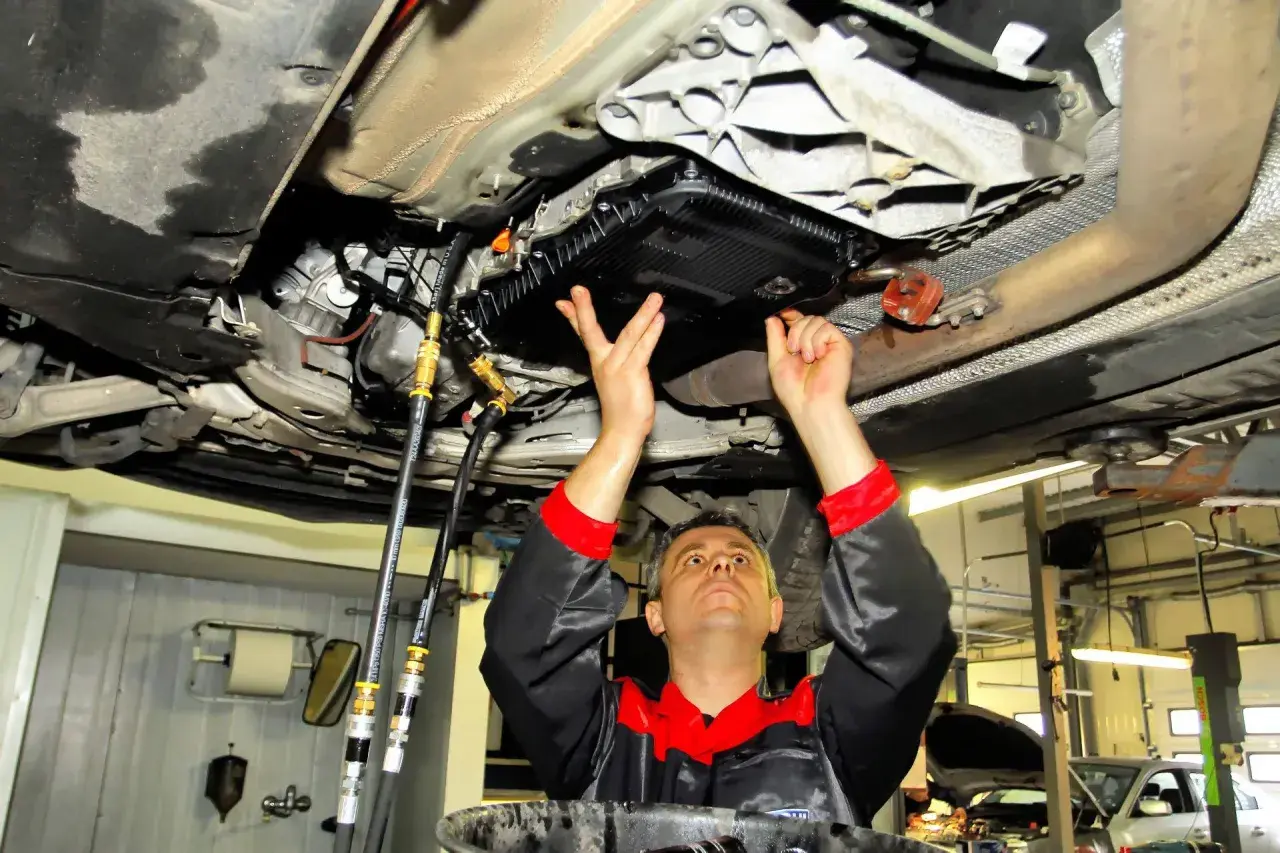 Mechanik wykonuje statyczną wymianę oleju w automatycznej skrzyni biegów, podłączając węże do układu.