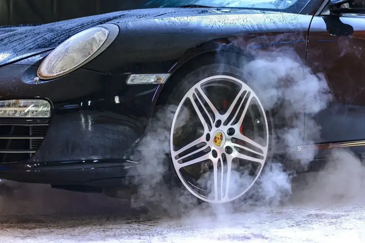 Czarny Porsche z dymem unoszącym się z koła. Zastanawiasz się, ozonowanie samochodu ile czasu zajmuje?