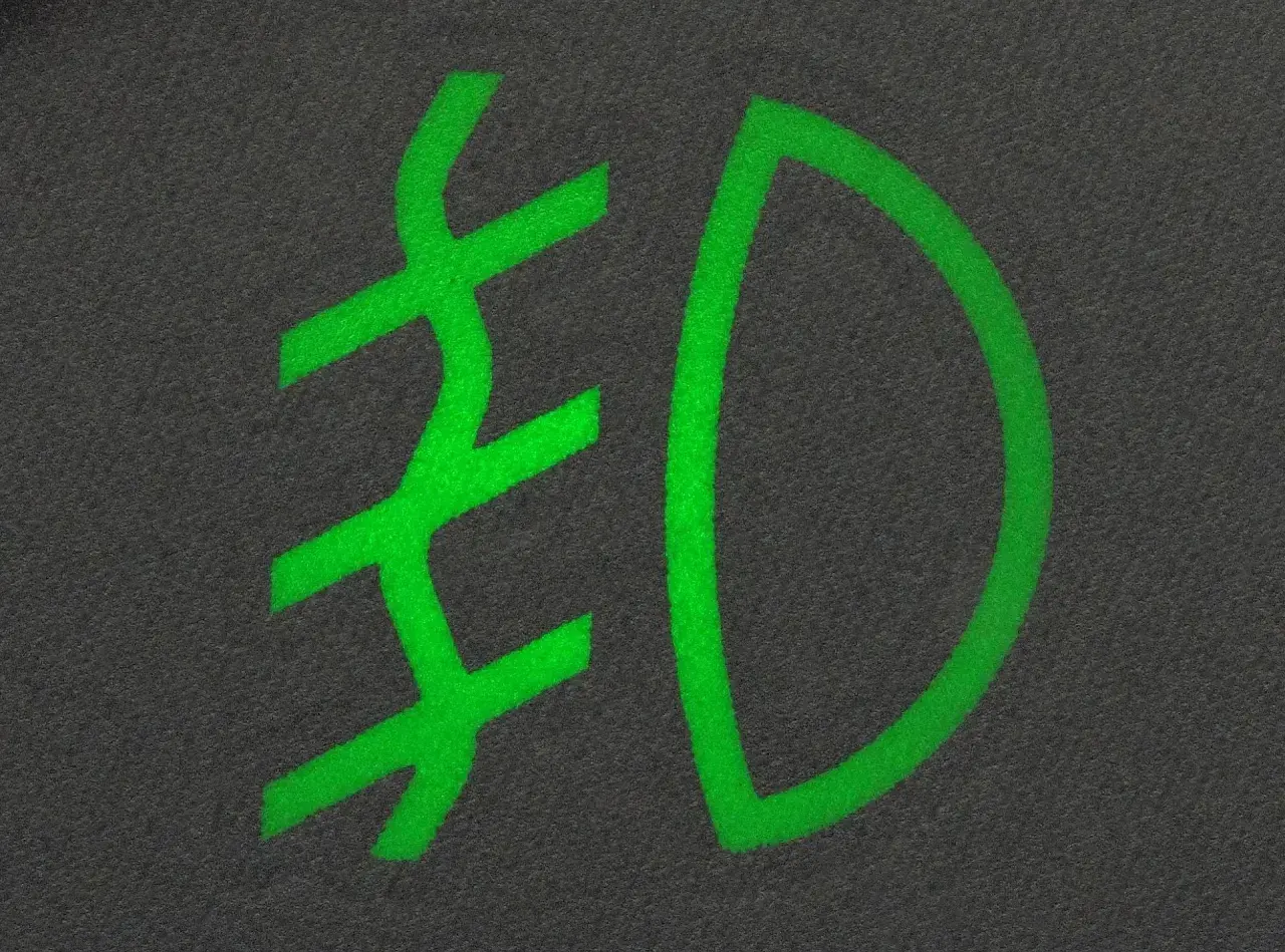 Zielony symbol przeciwmgielny na ciemnym tle.