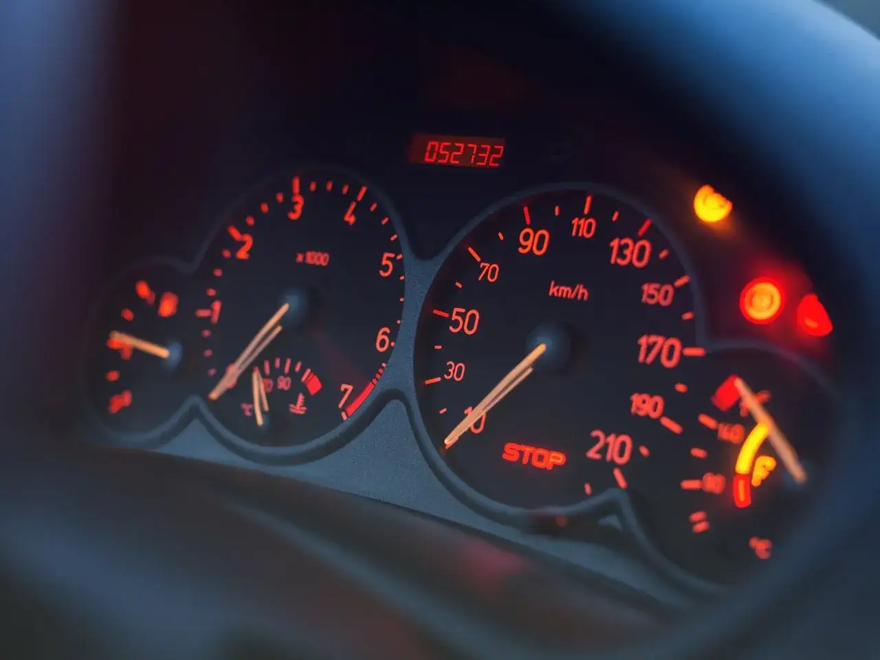Deska rozdzielcza samochodu Skoda z podświetlanymi na czerwono wskaźnikami. Widoczny prędkościomierz, obrotomierz i wskaźnik paliwa.